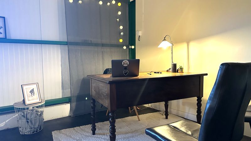 Le bureau en bois ancien du cabinet, éclairé par une lampe d'atelier